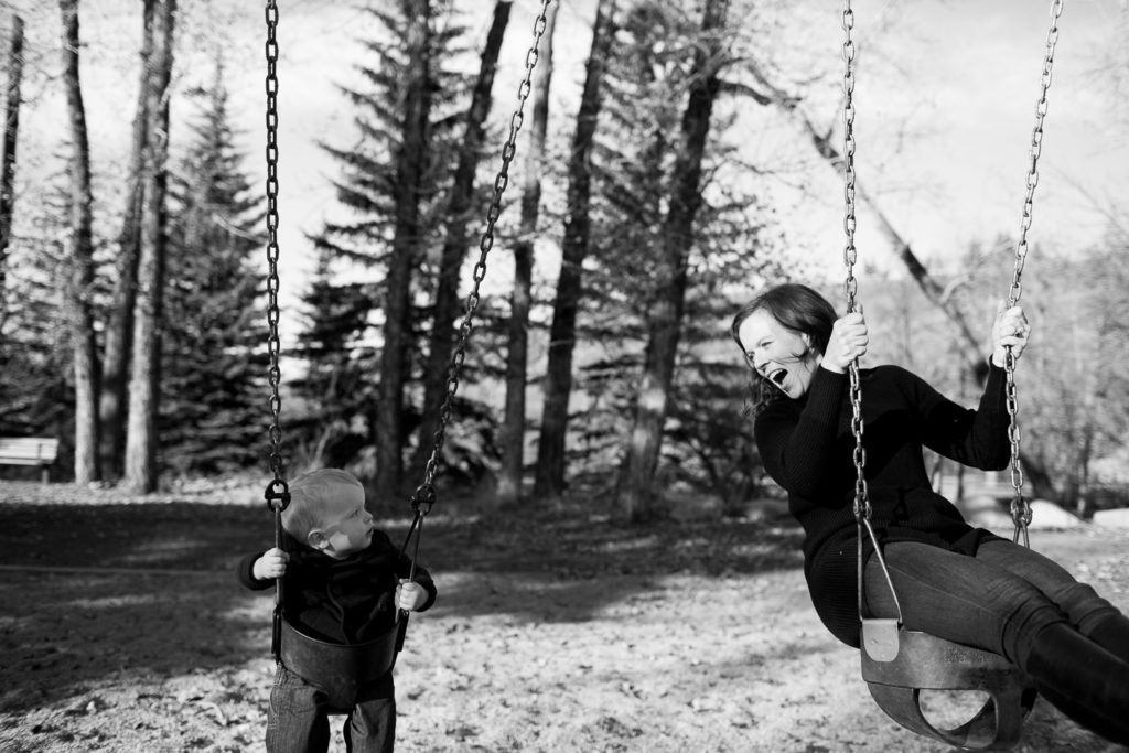 Mom playing on swings with son during family photography session