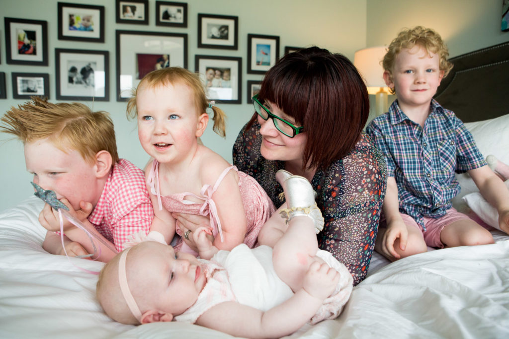 Mom with four kids on bed in Family photo shoot